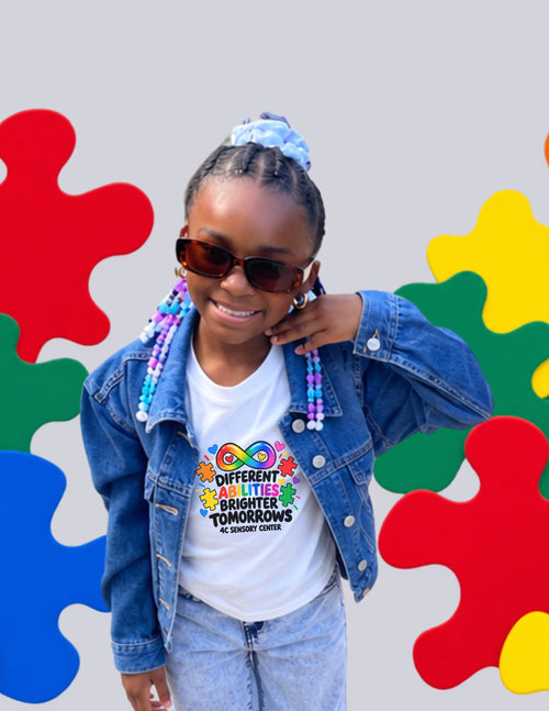 Girl in sunglasses and a denim jacket wearing the white Different Abilities, Brighter Tomorrows tee by 4C Sensory Center
