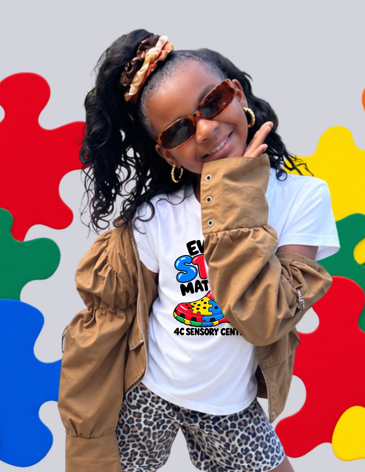 Girl in sunglasses and a tan jacket wearing the white Every Step Matters tee by 4C Sensory Center
